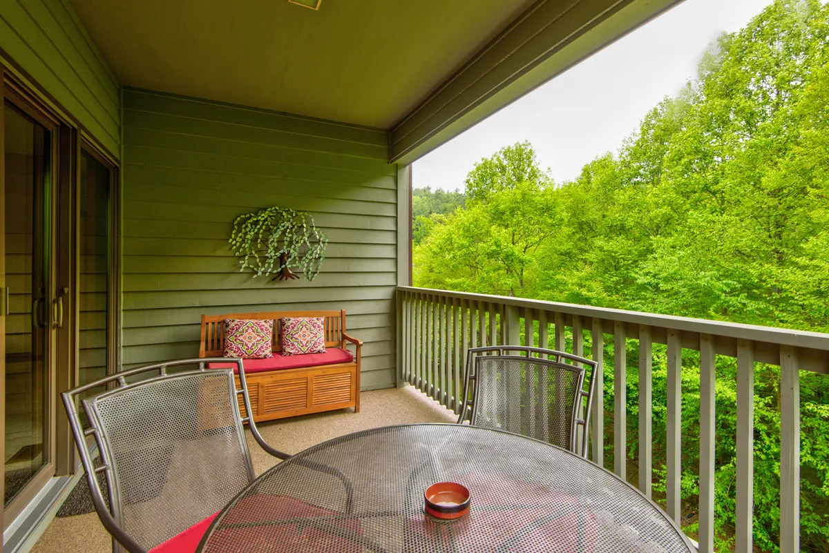 A cozy outdoor seating area with a table positioned to enjoy views of the surrounding greenery. The scene exudes tranquility, with filtered daylight suggesting a relaxing spot for coffee or conversation as part of the resort’s wellness and leisure experiences.