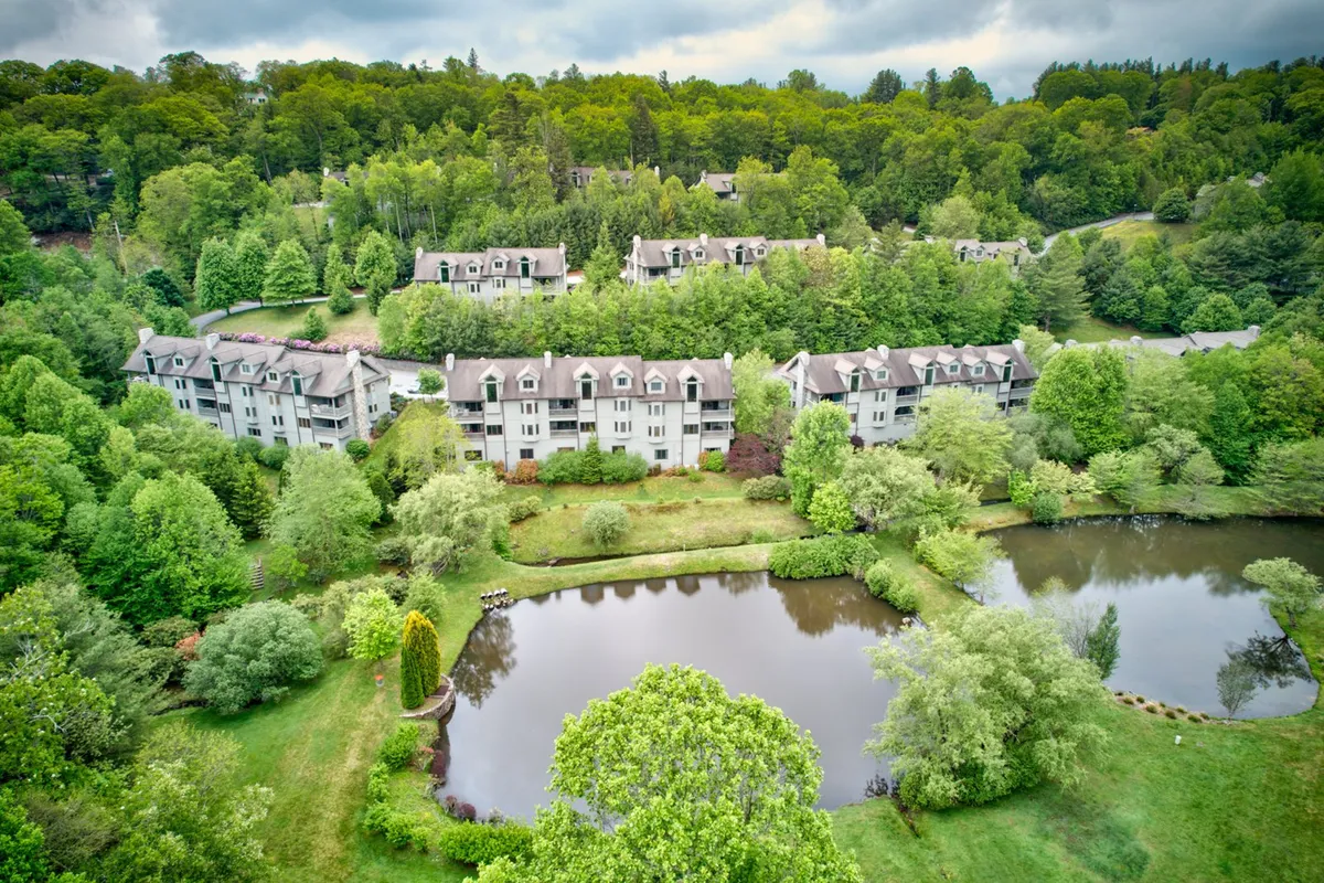 This image captures the resort's ponds surrounded by lush greenery, with apartment buildings in the background. Guests can be seen strolling along the water, relaxing, and enjoying the peaceful natural scenery as sunset casts a warm glow over the landscape.