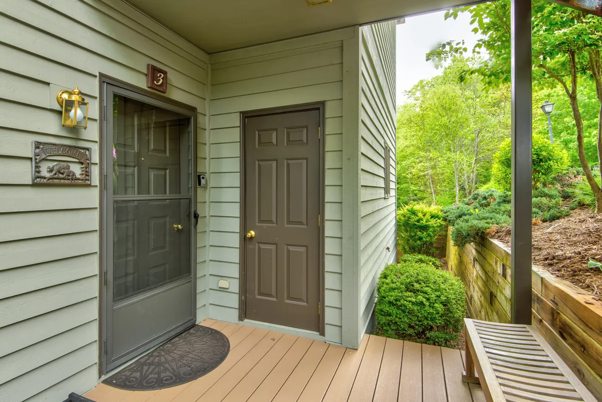 The welcoming front entrance of the condo, featuring a friendly 'Welcome' sign, a bench for seating, and well-maintained landscaped greenery. The scene feels approachable and hints at the start of a memorable stay with friends or couples.