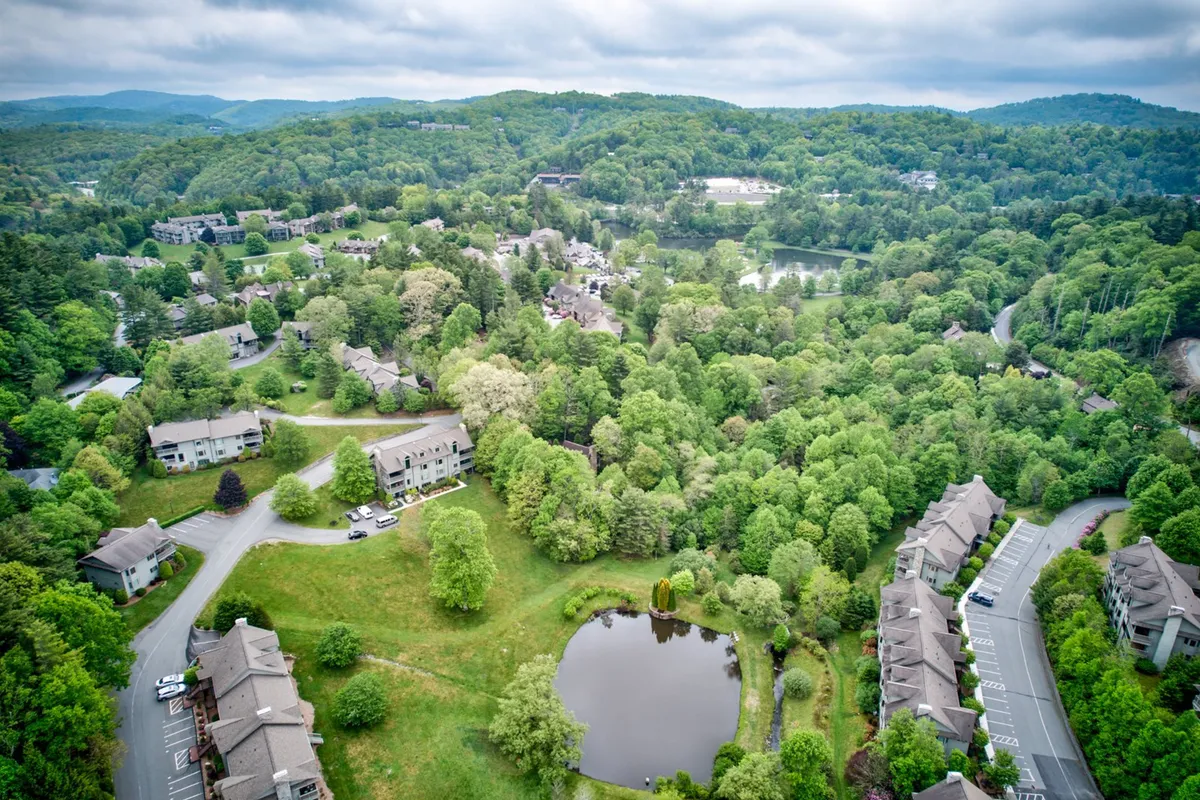 This tranquil view highlights a serene pond edged by greenery, residential buildings, and curving paths. The water reflects golden sunset hues, and the setting invites relaxation or a quiet walk with the family.
